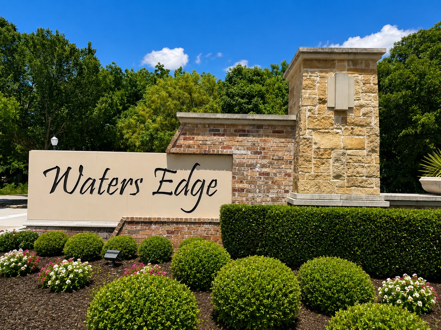 Stone entrance sign that reads Lake Pointe, set in a cream stone wall with blue sky and trees behind.
